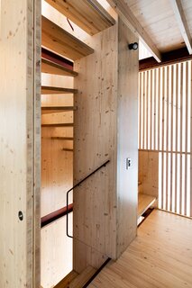 A staircase winds up through the center of the house. Its structural spine is made of cross-laminated timber, while the screen that encloses it is made from slats of South African pine. “The timber screen separates the stair from the surrounding space but still allows glimpses through,” says Douglas. “It recalls Japanese screens, especially at night when it lights up like a lantern.”