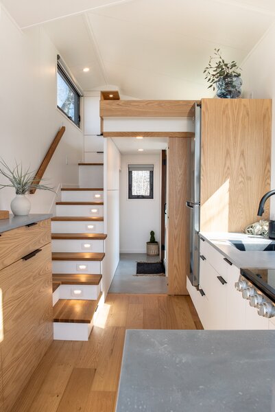 A staircase with white oak treads accesses the loft-style bedroom. The kitchen counters and bathroom flooring are crafted from concrete mixed with glass beads that give the material an organic feel and a lighter weight.