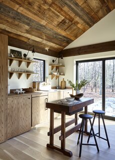 Custom oak cabinetry in the kitchenette was given a modern treatment to balance the more rustic elements in the setting, like the ceiling and antique table-turned-kitchen island. The faucet is by Kingston Brass.