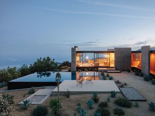 Designed by award-winning Sant Architects, this four-bedroom vacation rental near Topanga elevates the concept of a mountain retreat to new heights—from its raw, concrete facade and hillside pool, to the Bauhaus-inspired interiors that feature expansive glass walls that overlook the Pacific Ocean. The clean, architectural lines are expressed using iron beams, concrete slabs, timber-panelled walls, and glass, and the sprawling, open-plan living area features a slide-away fireplace and enormous windows that seamlessly transition the property from cosy winter retreat to breezy summer getaway.