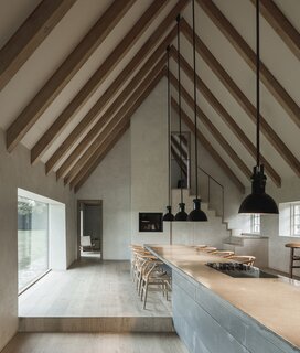 Project architects Studio Marshall Blecher and Jan Henrik Jansen Arkitekter opened up the center of the house, previously comprising a maze of fourteen small rooms,  creating one large and airy kitchen and dining space with a high, chapel like ceiling. A six-meter-long concrete plinth standing at the center of the room which doubles as an island bench and dining table, had to be lowered into the house by a crane while the roof was being reconstructed.