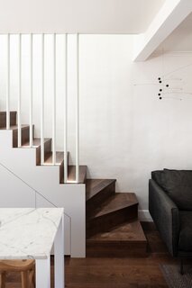 The staircase that accesses the second level features a slim silhouette that preserves ground space for the open-plan first level, where the kitchen, dining, and living areas are located.
