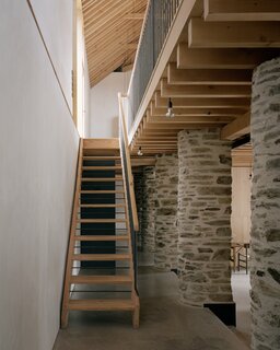 In a lightweight counterpoint to the preserved stone columns, the staircase is composed of floating wood tread and handcrafted metal spindles, fabricated by a local blacksmith.