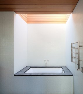 A large skylight looms above a Duravit tub and a Runtal Radia towel warmer in the en suite bathroom.