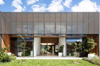 Perforated steel screens provide shading and privacy to the interior living spaces. The garden extends from the inner courtyard to the rear yard with open, connected spaces.