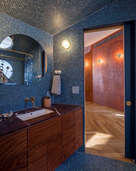 The bathroom is clad in blue penny tile, and natural light pours in to illuminate it all. “It’s almost a spa-like experience,” says Khoi. The tiles are from Bedrosians.
