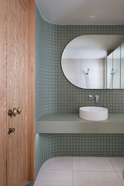 The use of green mosaic tiles in the bathroom is a "polite homage" to the balcony's original green mosaic floor tiles. 